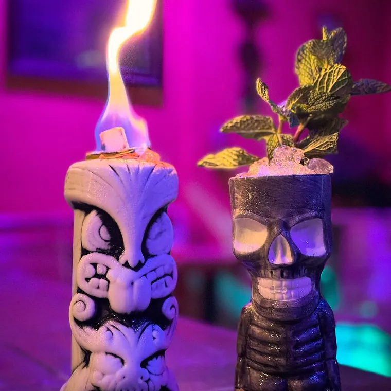 A flaming tiki mug garnished with fresh mint on the bar at The Tipsy Skipper