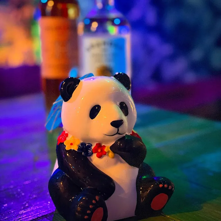 A cocktail served in a ceramic panda tiki mug with a flower lei at The Tipsy Skipper